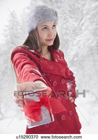 Woman grudgingly holding out a Christmas gift View Large Photo Image Stock Image - Woman grudgingly holding out a Christmas gift. Fotosearch