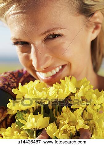 Stock Photo - Woman holding yellow flowers. Fotosearch