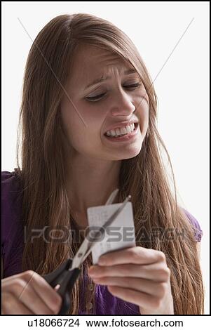 Picture - Woman reluctantly cutting her credit card. Fotosearch