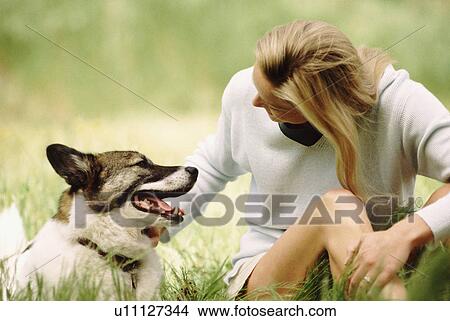 Woman sitting in meadow with dog View Large Photo Image Picture - Woman sitting in meadow with dog. Fotosearch