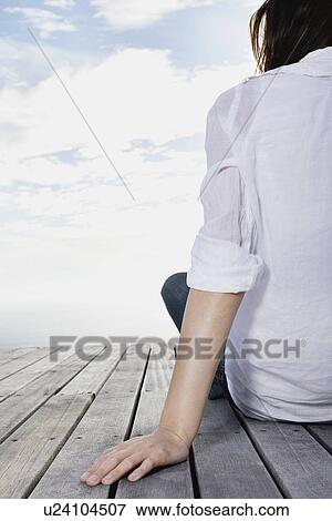 Stock Photo - Woman sitting on dock. Fotosearch