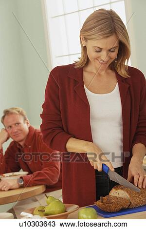Woman slicing bread and her husband watches View Large Photo Image Stock Image - Woman slicing bread and her husband watches. Fotosearch