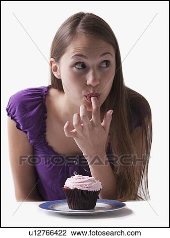 Woman sneaking a lick of icing from a cupcake View Large Photo Image Stock Image - Woman sneaking a lick of icing from a cupcake. Fotosearch