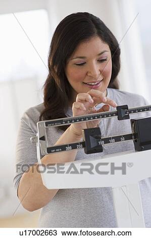Stock Image - Woman standing on scale. Fotosearch