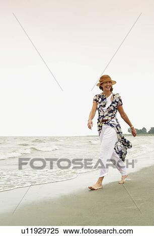 Stock Photography - Woman walking on the beach. Fotosearch