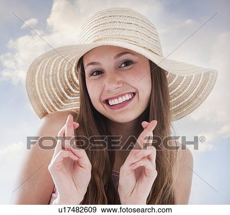 Woman wearing a straw hat and crossing her fingers View Large Photo Image Stock Photo - Woman wearing a straw hat and crossing her fingers. Fotosearch