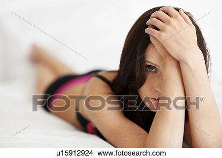 Picture - Woman wearing bra and underwear lying on bed. Fotosearch