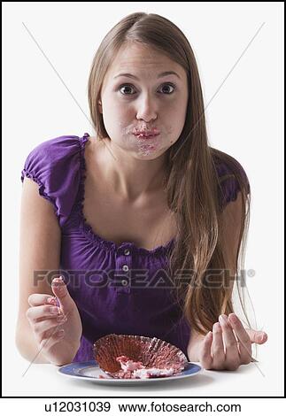 Stock Photo - Woman with a cupcake stuffed in her mouth. Fotosearch