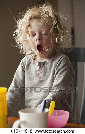 Stock Image - Yawning child at the breakfast table. Fotosearch