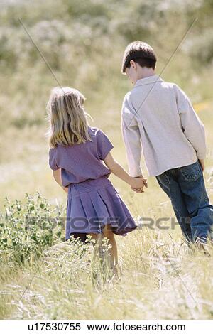 Young boy and girl walking hand in hand in meadow View Large Photo Image Stock Photography - Young boy and girl walking hand in hand in meadow. Fotosearch
