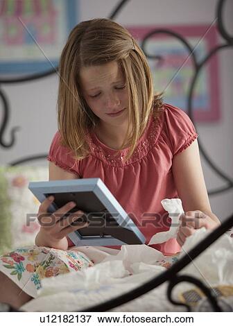 Young girl crying while looking at photograph View Large Photo Image Stock Photo - Young girl crying while looking at photograph. Fotosearch