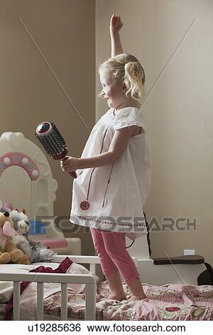 Stock Photograph - Young girl dancing on her bed. Fotosearch