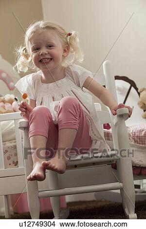 Young girl in rocking chair eating a sucker View Large Photo Image Picture - Young girl in rocking chair eating a sucker. Fotosearch