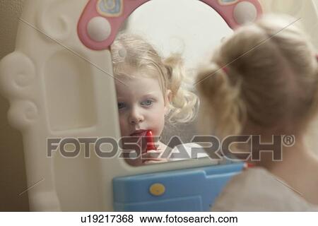 Stock Photo - Young girl putting on lipstick. Fotosearch