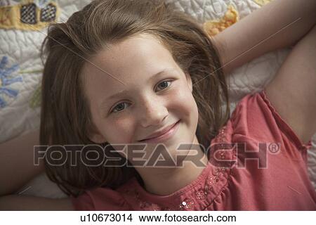Picture - Young girl relaxing on her bed. Fotosearch