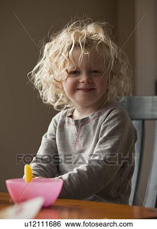 Stock Photograph - Young girl sitting at breakfast table. Fotosearch
