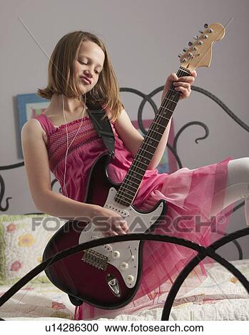 Young girls playing guitar on her bed View Large Photo Image Stock Image - Young girls playing guitar on her bed. Fotosearch