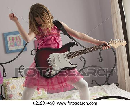 Young girls playing guitar on her bed View Large Photo Image Stock Image - Young girls playing guitar on her bed. Fotosearch