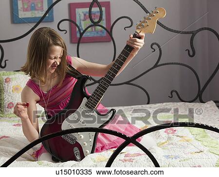 Young girls playing guitar on her bed View Large Photo Image Stock Photography - Young girls playing guitar on her bed. Fotosearch