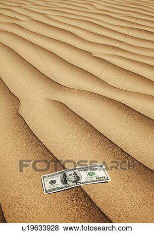 Stock Photo - 100 dollar bill on sand in desert. Fotosearch