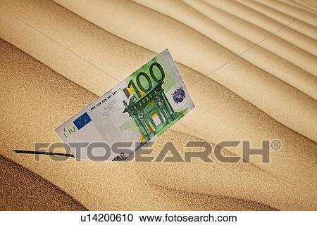 Stock Image - 100 euro bill in sand. Fotosearch