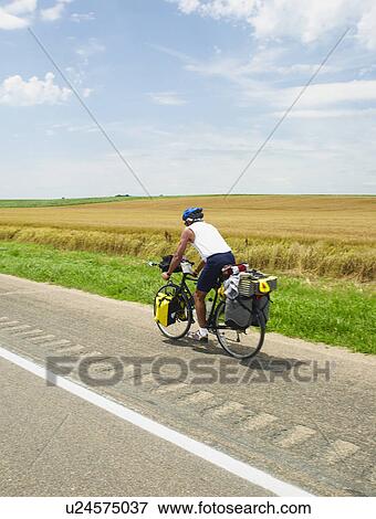 Adventure cyclist biking on rural road View Large Photo Image Stock Photo - Adventure cyclist biking on rural road. Fotosearch