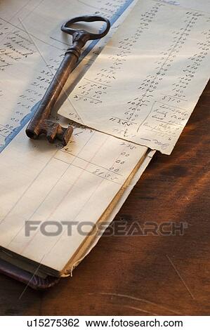 Stock Image - Antique key on top of ledger. Fotosearch