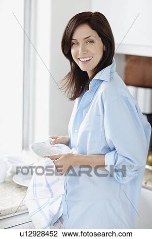 Stock Image - Attractive brunette drying the dishes. Fotosearch