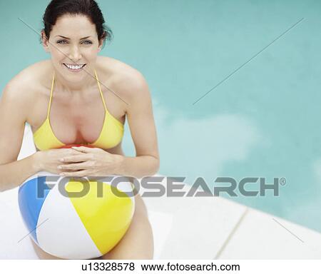Stock Photo - Attractive brunette holding a beach ball. Fotosearch