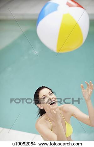 Picture - Attractive brunette playing with a beach ball. Fotosearch