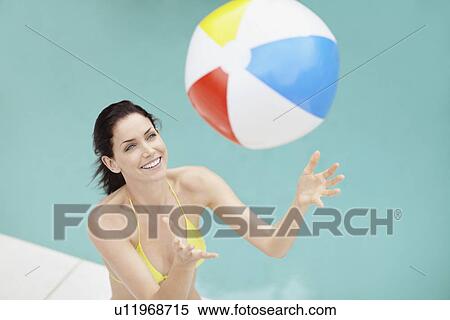 Stock Photography - Attractive brunette playing with a beach ball. Fotosearch