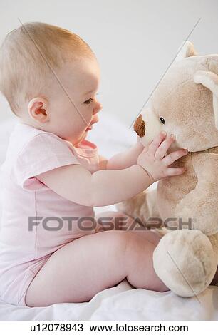 Stock Image - Baby playing with teddy bear. Fotosearch