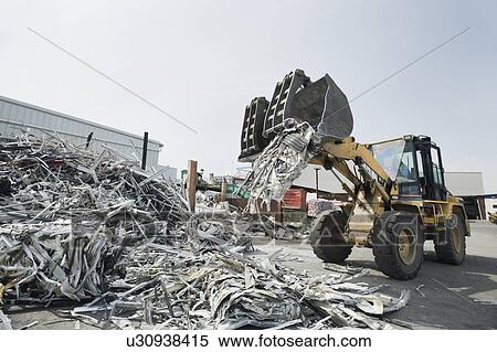 Stock Photography - Backhoe dumping recyclable metal. Fotosearch