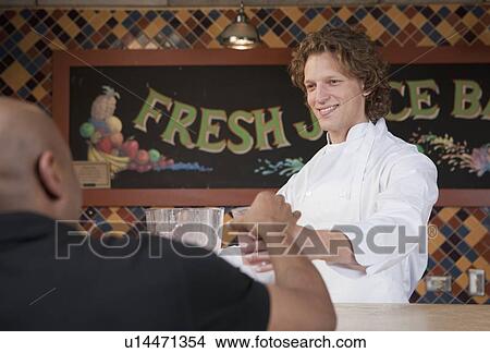 Picture - Bartender and customer at juice bar. Fotosearch