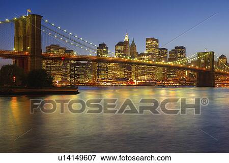 Stock Photo - Brooklyn Bridge and Jersey City buildings at night. Fotosearch