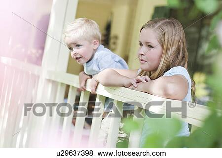 Stock Photo - Brother and sister gazing over porch railing. Fotosearch