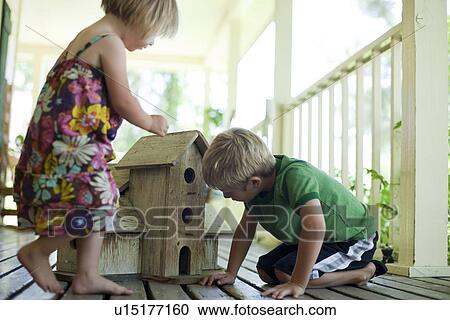 Stock Image - Brother and sister looking at birdhouse. Fotosearch