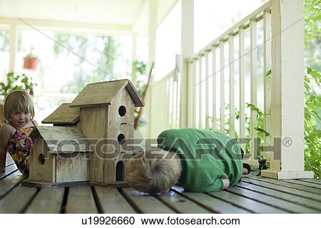 Stock Image - Brother and sister looking at birdhouse. Fotosearch