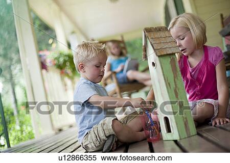 Stock Photography - Brother and sister painting birdhouse together. Fotosearch