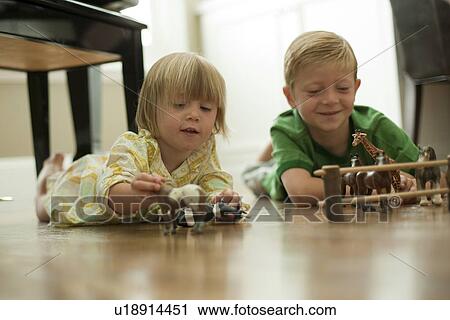 Stock Image - Brother and sister playing with toy animals. Fotosearch