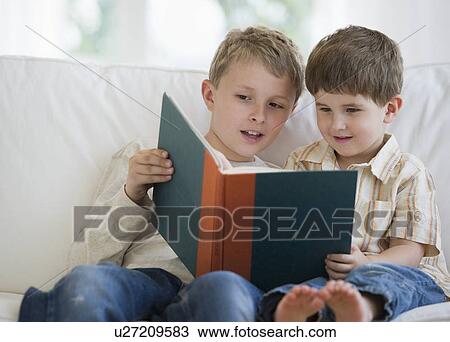 Stock Image - Brothers reading a book together. Fotosearch