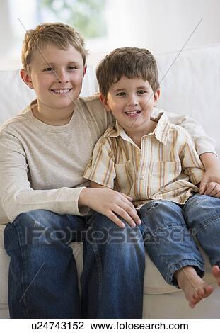 Stock Image - Brothers sitting on couch together. Fotosearch