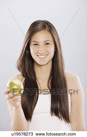 Brunette woman holding an apple View Large Photo Image Stock Image - Brunette woman holding an apple. Fotosearch