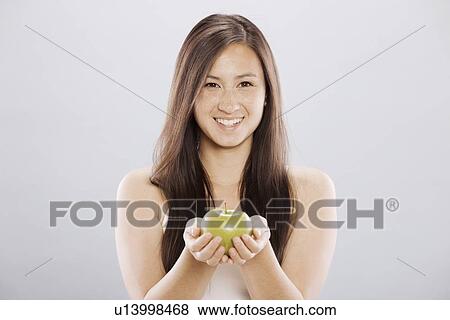 Brunette woman holding an apple View Large Photo Image Stock Photo - Brunette woman holding an apple. Fotosearch