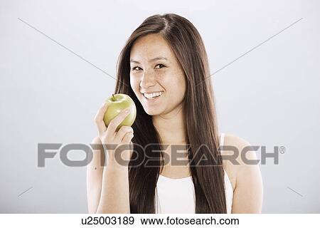 Stock Photo - Brunette woman holding an apple. Fotosearch