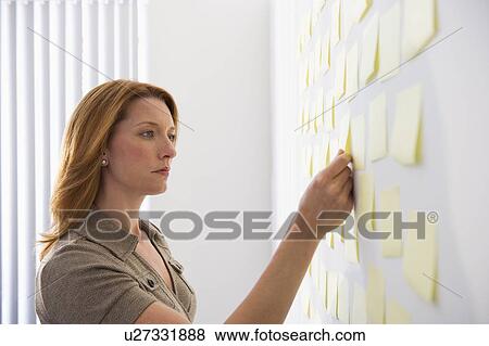 Businesswoman putting sticky note on wall View Large Photo Image Stock Photo - Businesswoman putting sticky note on wall. Fotosearch