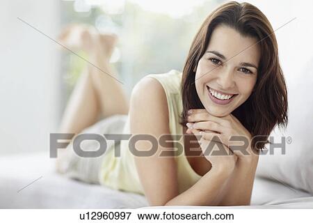 Cheerful brunette woman relaxing on couch View Large Photo Image Stock Photo - Cheerful brunette woman relaxing on couch. Fotosearch