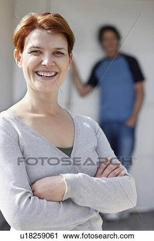 Stock Image - Cheerful woman standing with her arms crossed. Fotosearch