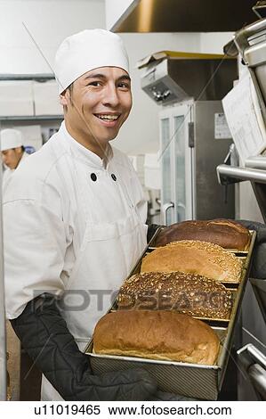 Stock Photography - Chef holding tray of freshly baked bread. Fotosearch