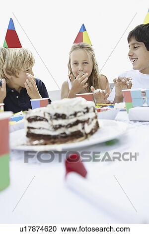 Stock Image - Children eating birthday cake. Fotosearch